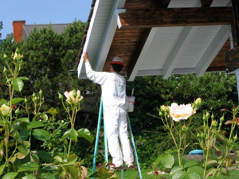 Maler streicht eine Dachuntersicht über einem Rosengarten