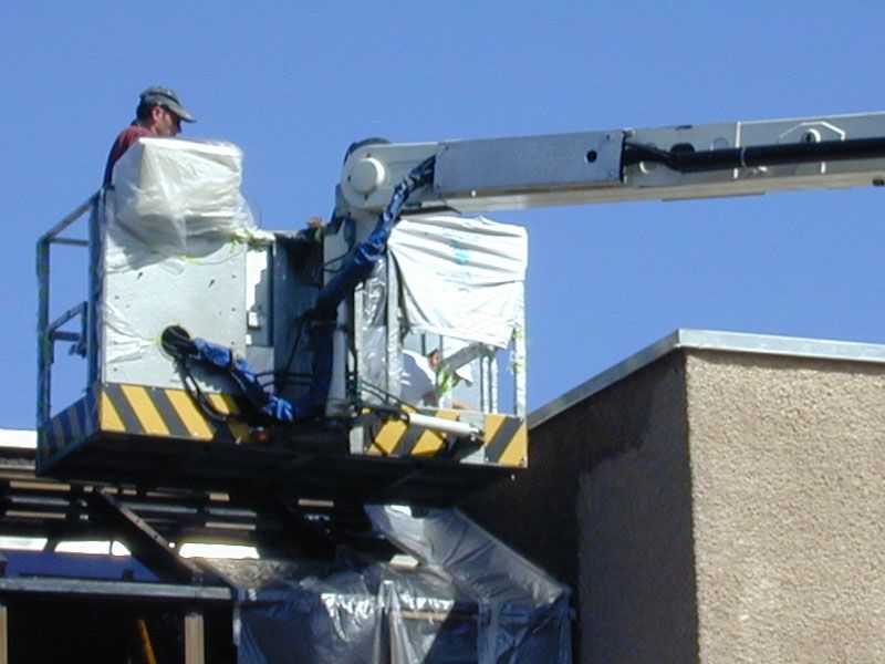 Maler arbeitet auf einer Hebebühne an einem Flachdachgebäude